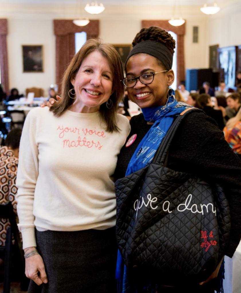 Jennifer Weiss-Wolf and Jamia Wilson. Jennifer's Lingua Franca sweater reads "your voice matters." Jamia's tote reads "give a damn."