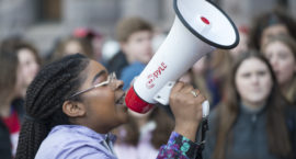a young girl holds a megaphone at a protest