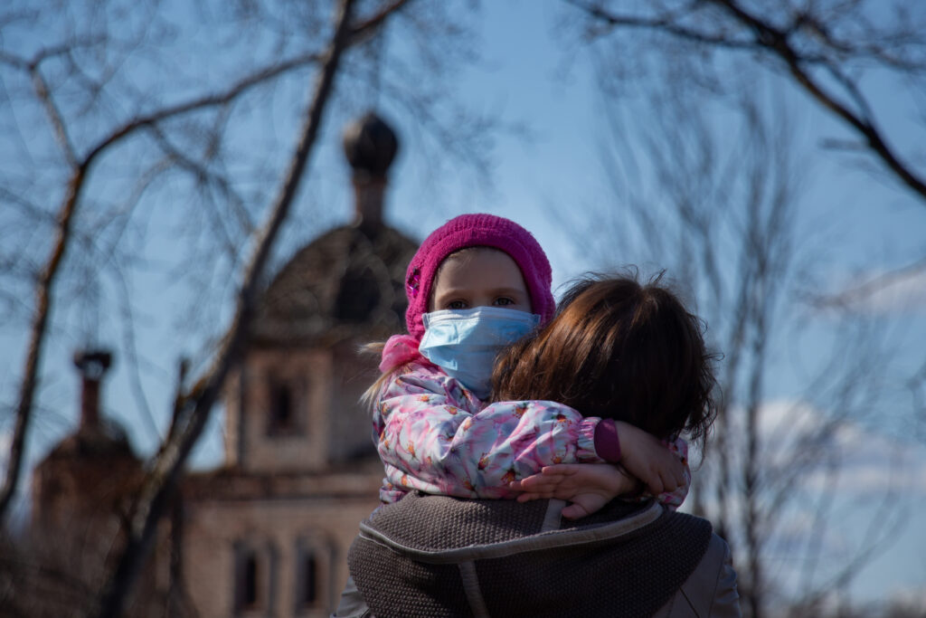 Stock image of a woman holding a child wearing a mask.