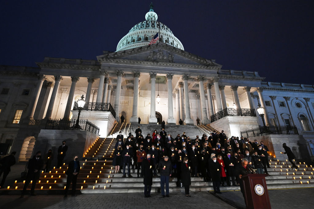 Lawmakers stand on the U.S. Capitol steps at night to mark the anniversary of the Jan. 6 insurrection
