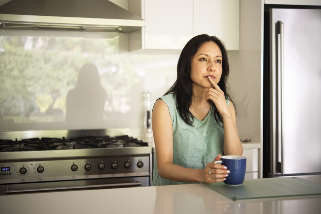 A woman contemplates divorce while drinking coffee in her kitchen