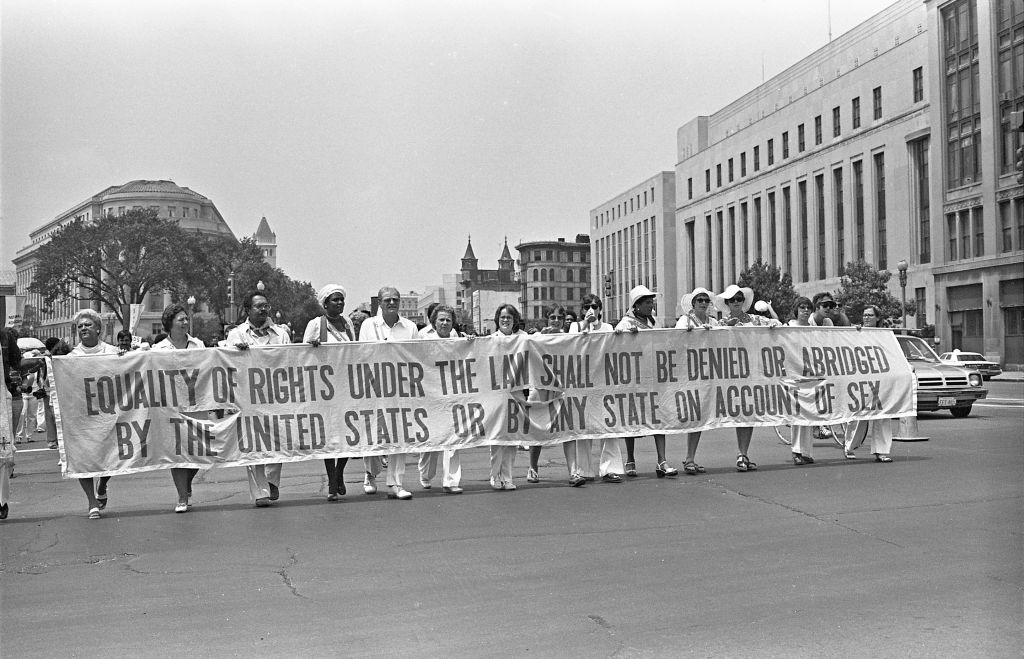 Demonstrators hold a sign: "Equality of rights under the law shall not be denied or abridged by the United States or by any State on account of sex."