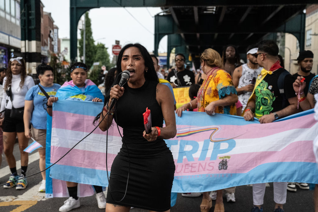 Trans rights activists march with a trans pride flag under a bridge in Queens, New York City.