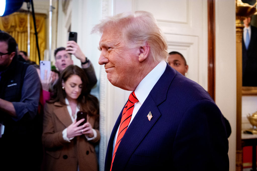 Trump smiles grimly in side profile as he walks to sign an anti-trans executive order