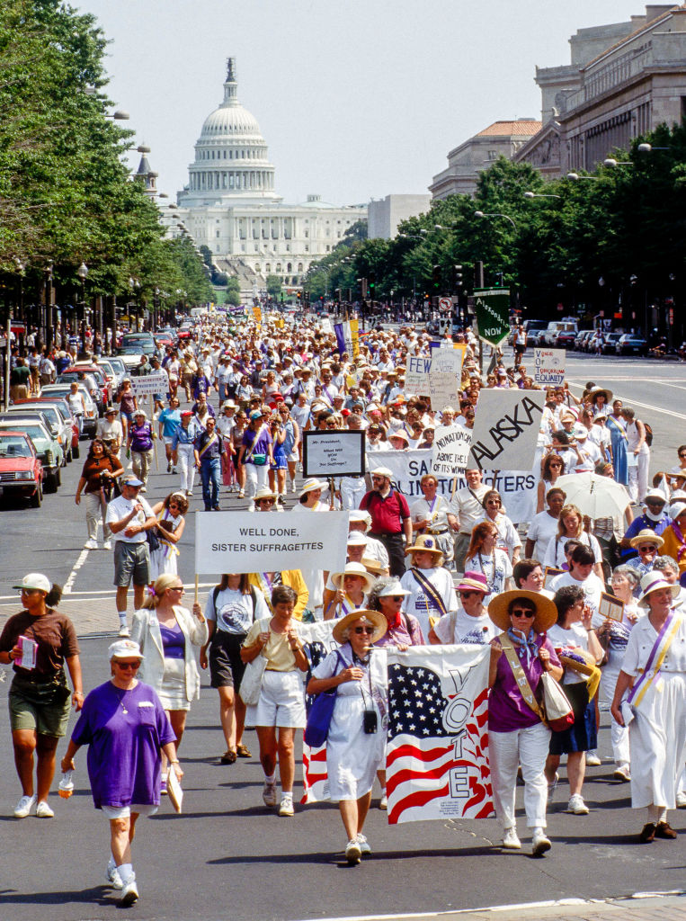 View of marchers as they walk along Pennsylvania Avenue. Visible in the center background is the United States Capitol Building.