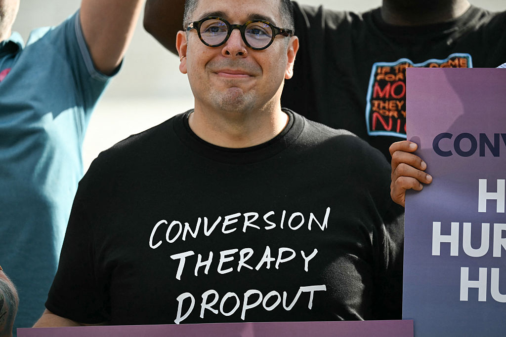 A man wears a shirt reading "conversion therapy dropout"
