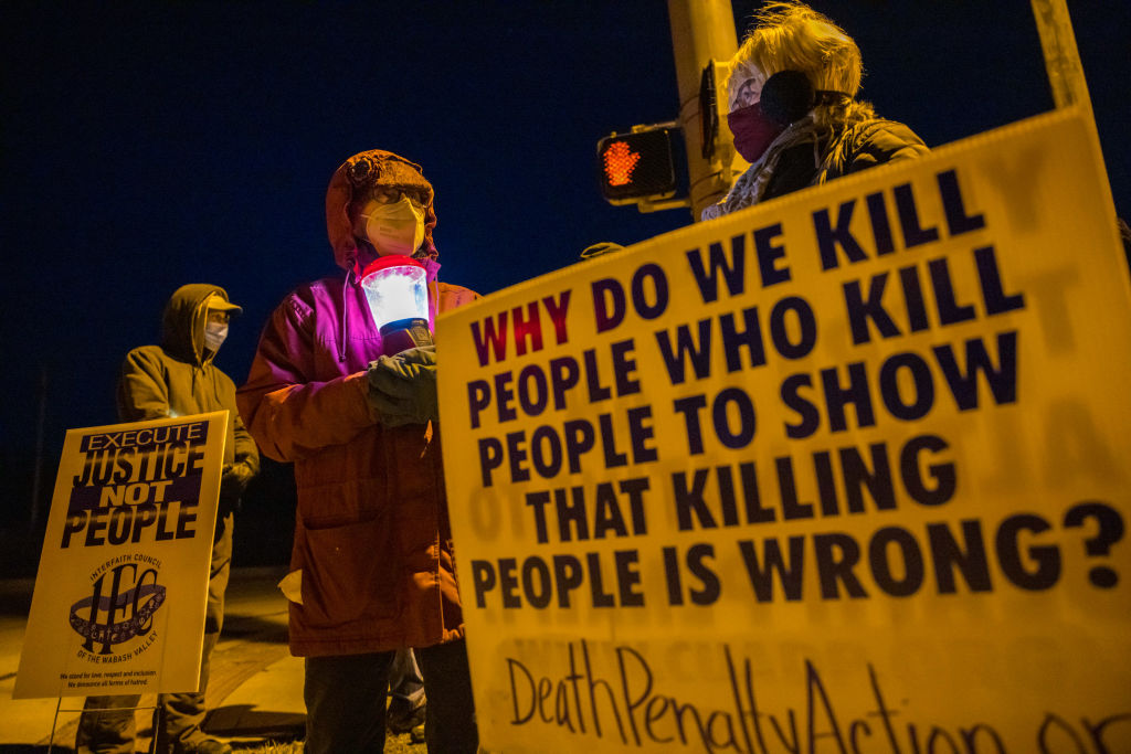 Signs read, "Execute justice not people" and "why do we kill people who kill people to show that killing people is wrong?"