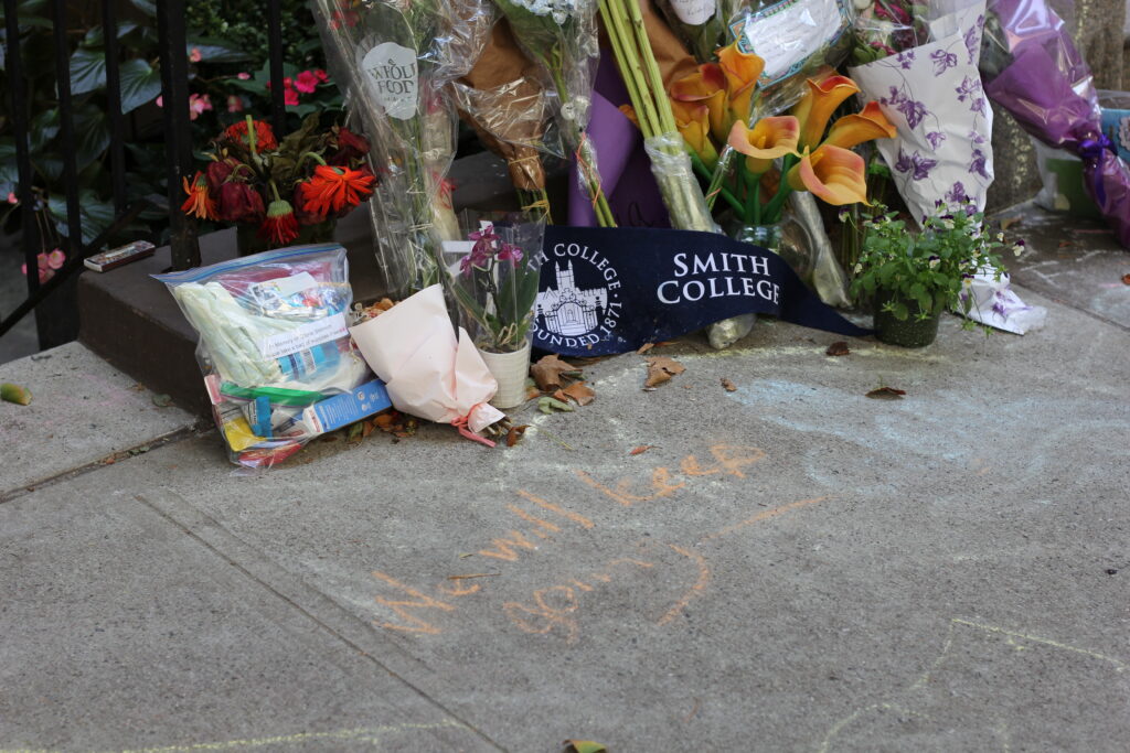 Bouquets of flowers and a Smith College flag lay on the sidewalk outside Gloria Steinem's apartment after her death. 