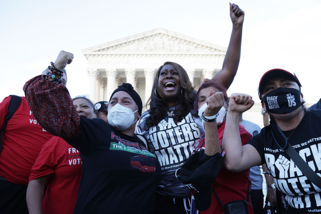 A group, including LaTosha Brown, yells and raises their fists at a voting rights demonstration. 