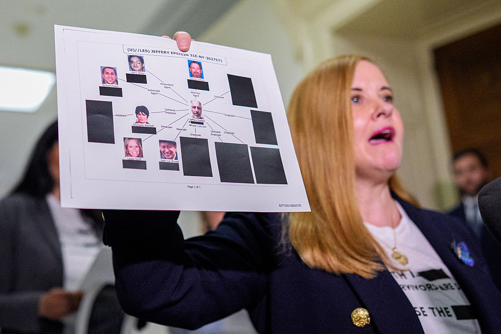 A woman holds up an infographic with Epstein at the center.
