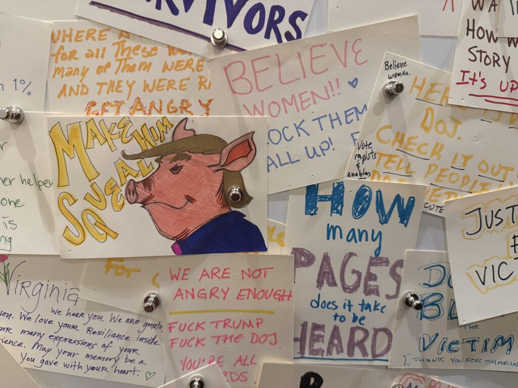 A bulletin board has notes advocating for the release of the Epstein files and denouncing President Trump. One piece of paper has a drawing of Trump as a pig.