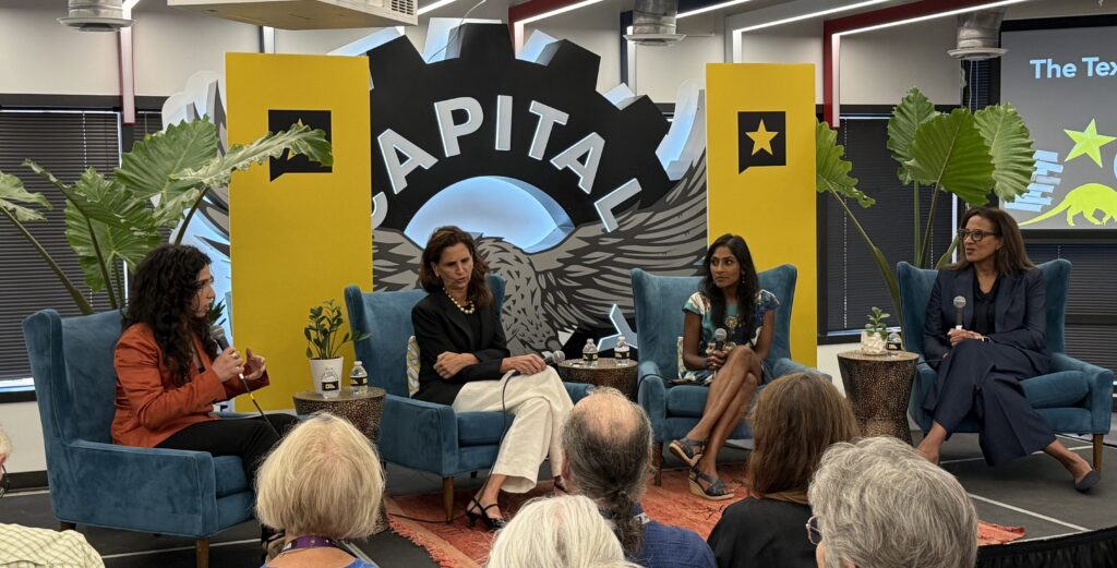 Carine Hajjar, Elizabeth Kennedy Trudeau, Krish O'Mara Vignarajah and Nicole Bibbins Sedeca sit together on a stage speaking to a crowd. 