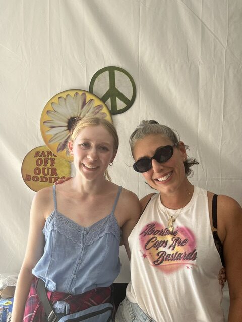 Ms. writer Ava Slocum, a blond woman wearing a blue tank top, stands next to Jessica Valenti, a woman with graying hair wearing a white tank top and sunglasses.