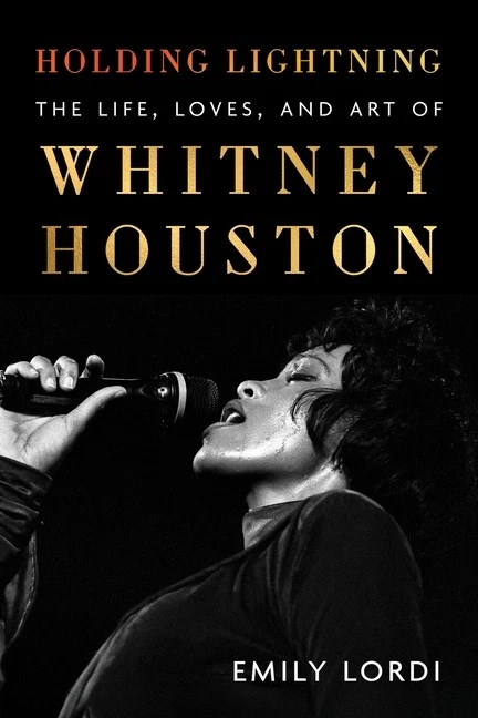 The cover of the book Whitney Houston by Emily Lordy displays a black and white cover photo of her singing soulfully into a raised microphone.
